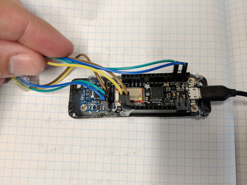 The first 3d-printed frame to hold the Adafruit Feather and accelerometer sensor.